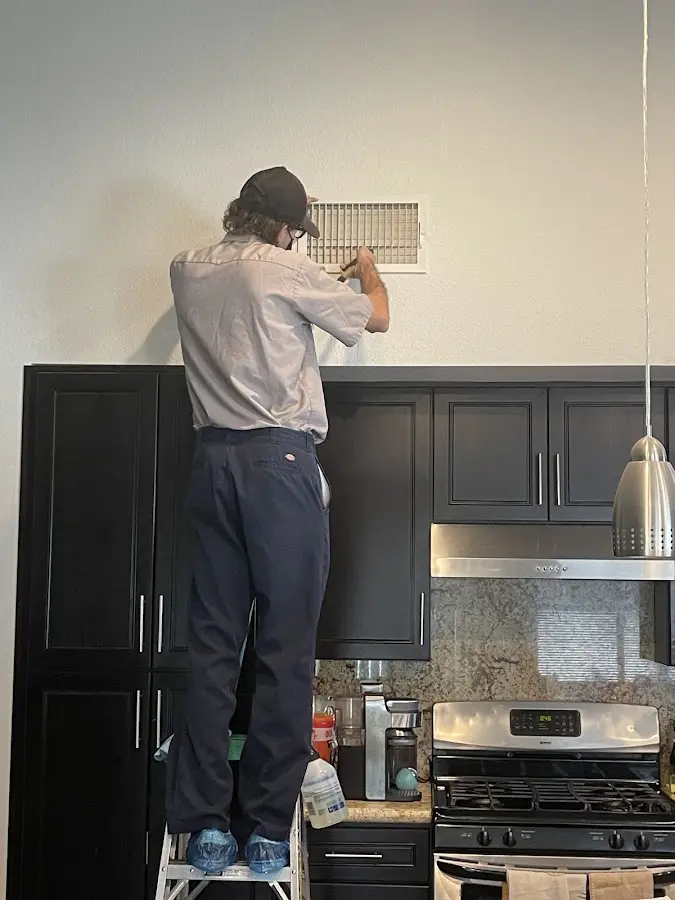 Technician inspecting an air vent during HVAC service in Irvington